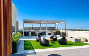A rooftop patio with a grill, seating area, and city views.
