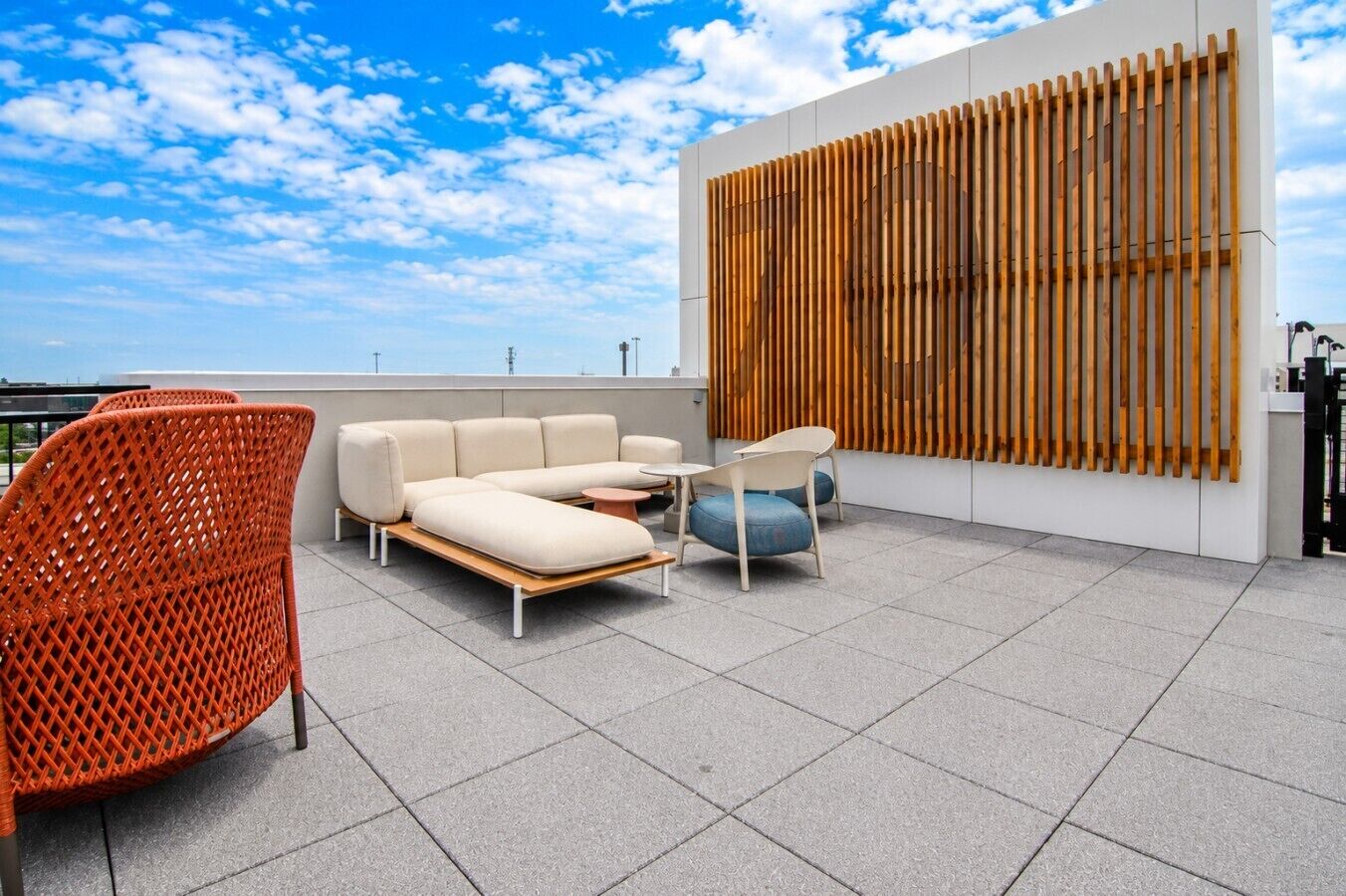 A rooftop terrace with a sofa, chairs, and a table.