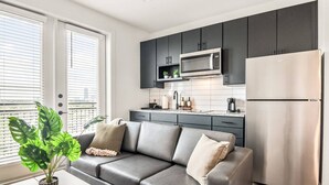 A modern kitchen with dark cabinets, a stainless steel refrigerator, and a microwave.