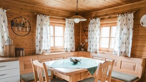 A cozy cabin interior with a wooden dining table, four chairs, and a bench.