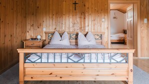 A wooden-paneled room with a bed, nightstand, and a cross on the wall.