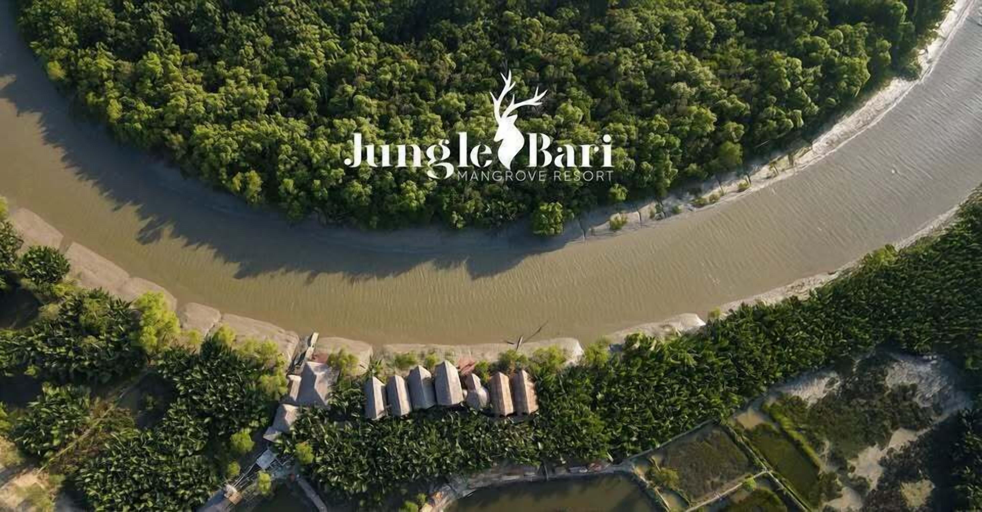 An aerial view of Jungle Bari Mangrove Resort with a river, dense mangrove forest, and several structures along the riverbank.