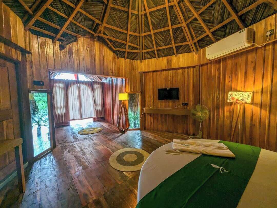 Una habitación de madera con una cama, un televisor y una ventana.