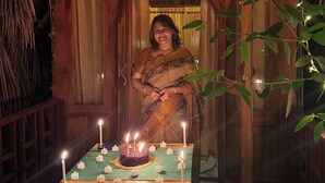 A woman in a traditional sari standing in a wooden hut with a thatched roof, decorated with string lights and candles. - JungleBari Mangrove Resort (Dacope)