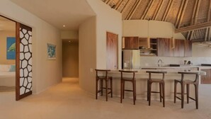 Cozinha moderna com ilha curva, banquetas de madeira e teto de palha.