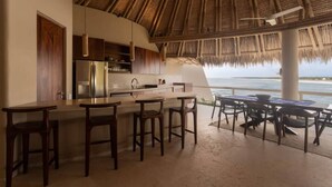 Uma cozinha com área de bar, conjunto de jantar e vista para o oceano.