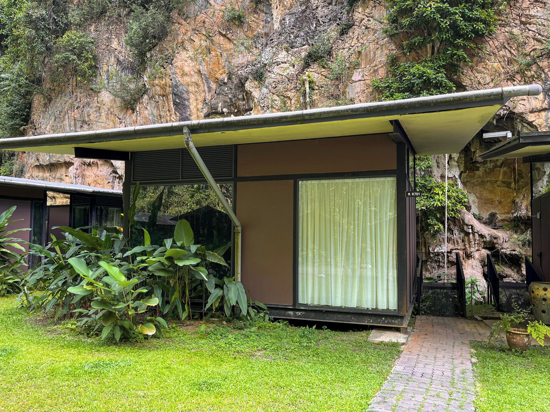 Un edificio moderno con un vestíbulo cubierto, un gran ventanal y vistas a un acantilado rocoso.