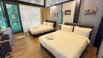A hotel room with two beds, a large window with curtains, and a view of greenery outside.