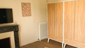 A bedroom with a bed, a wardrobe, a radiator, and a television.