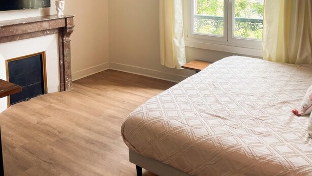 A bedroom with a bed, a television, a fireplace, and a window with curtains. - L'Angevin-4 pers-espace repas-Centre ville/Gare station (Le Mans)
