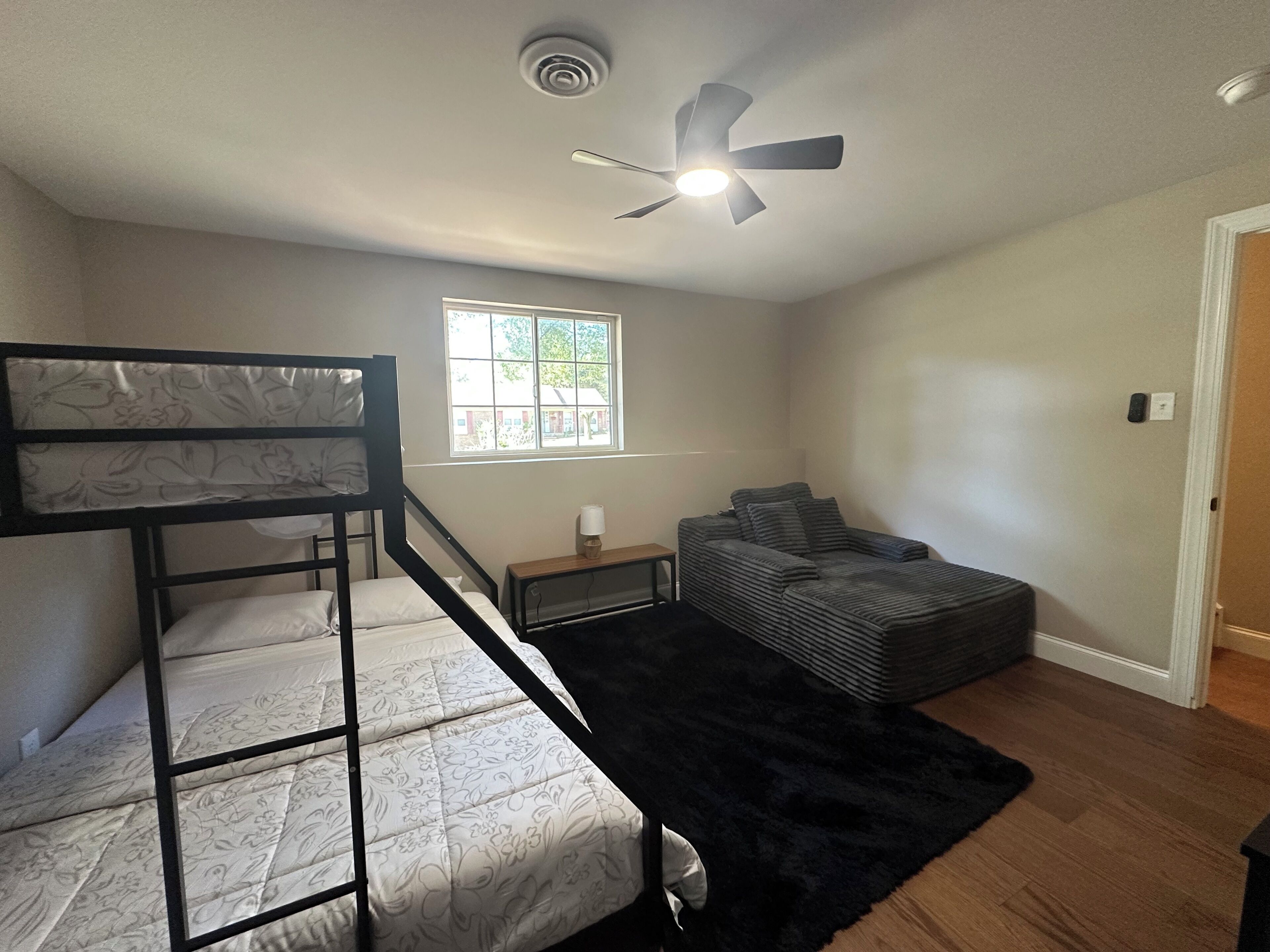 A bedroom with bunk beds, a window, a ceiling fan, and a black rug.