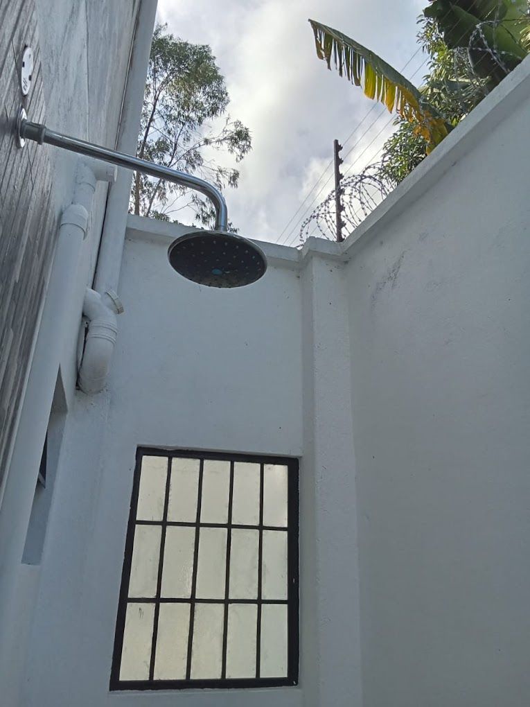 A small, enclosed space with a window and a showerhead.