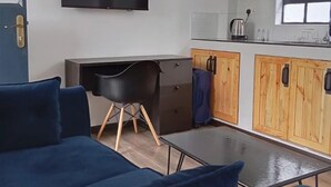 Een knus woongedeelte met een bank, een bureau, een televisie en houten kasten.