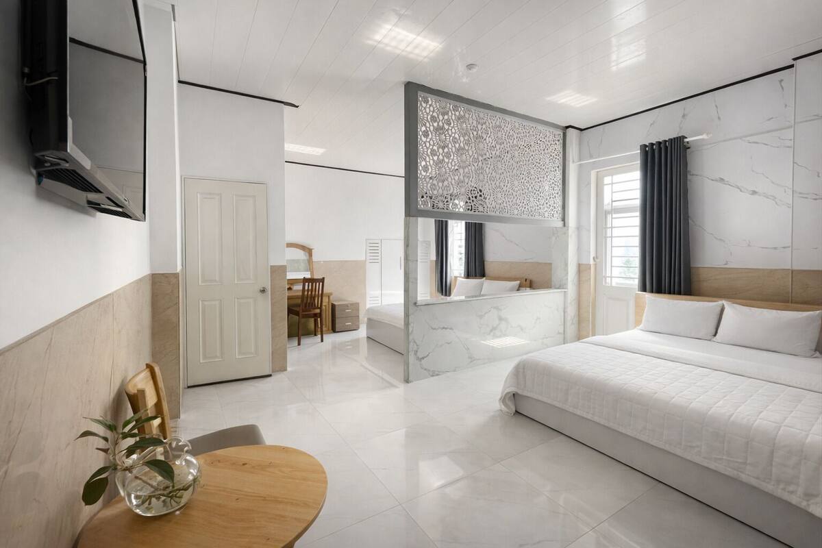 A modern hotel room with a large bed, a desk, and a seating area.