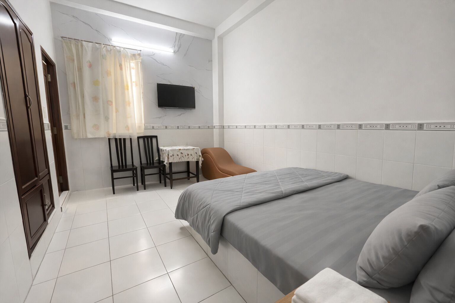Un dormitorio con cama, escritorio, dos sillas, televisor y puerta de baño.