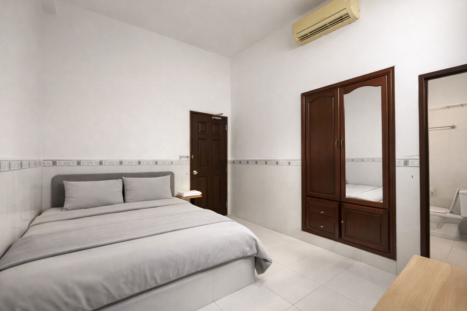 Ein Schlafzimmer mit Bett, Kleiderschrank, Nachttisch und Klimaanlage.