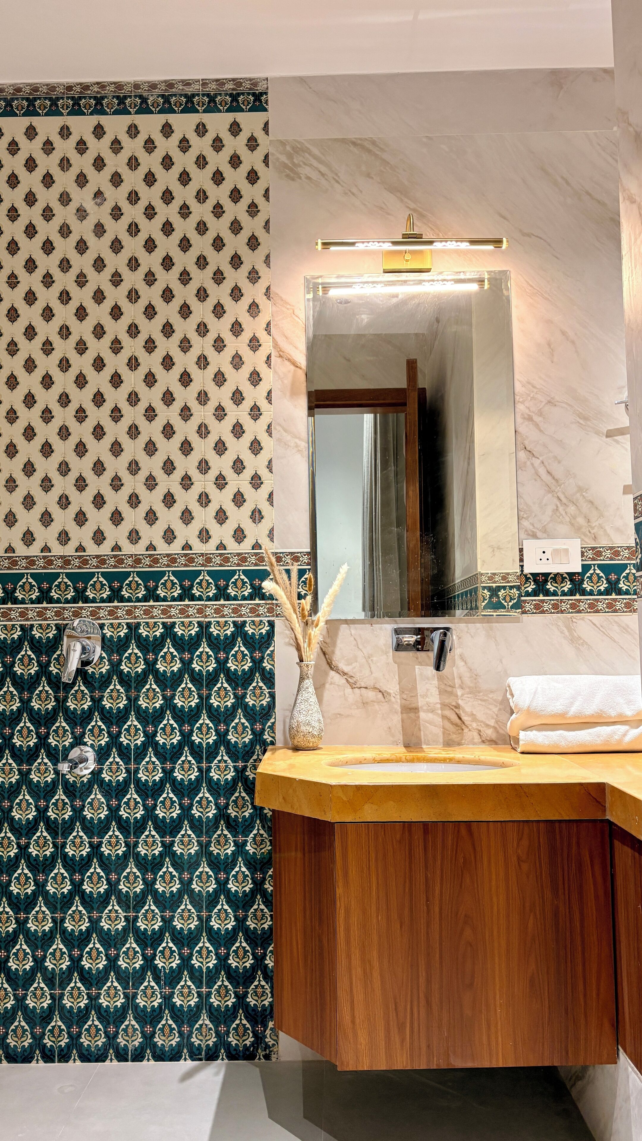 Une salle de bain avec un meuble-lavabo en bois, un miroir et des carreaux à motifs.