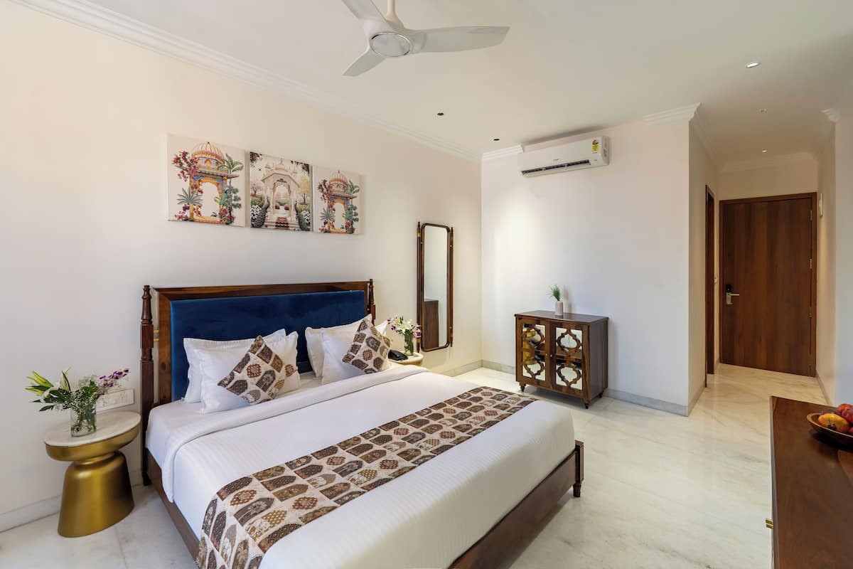 Hotelkamer met een groot bed, een plafondventilator, een wandairconditioner en een decoratieve spiegel.