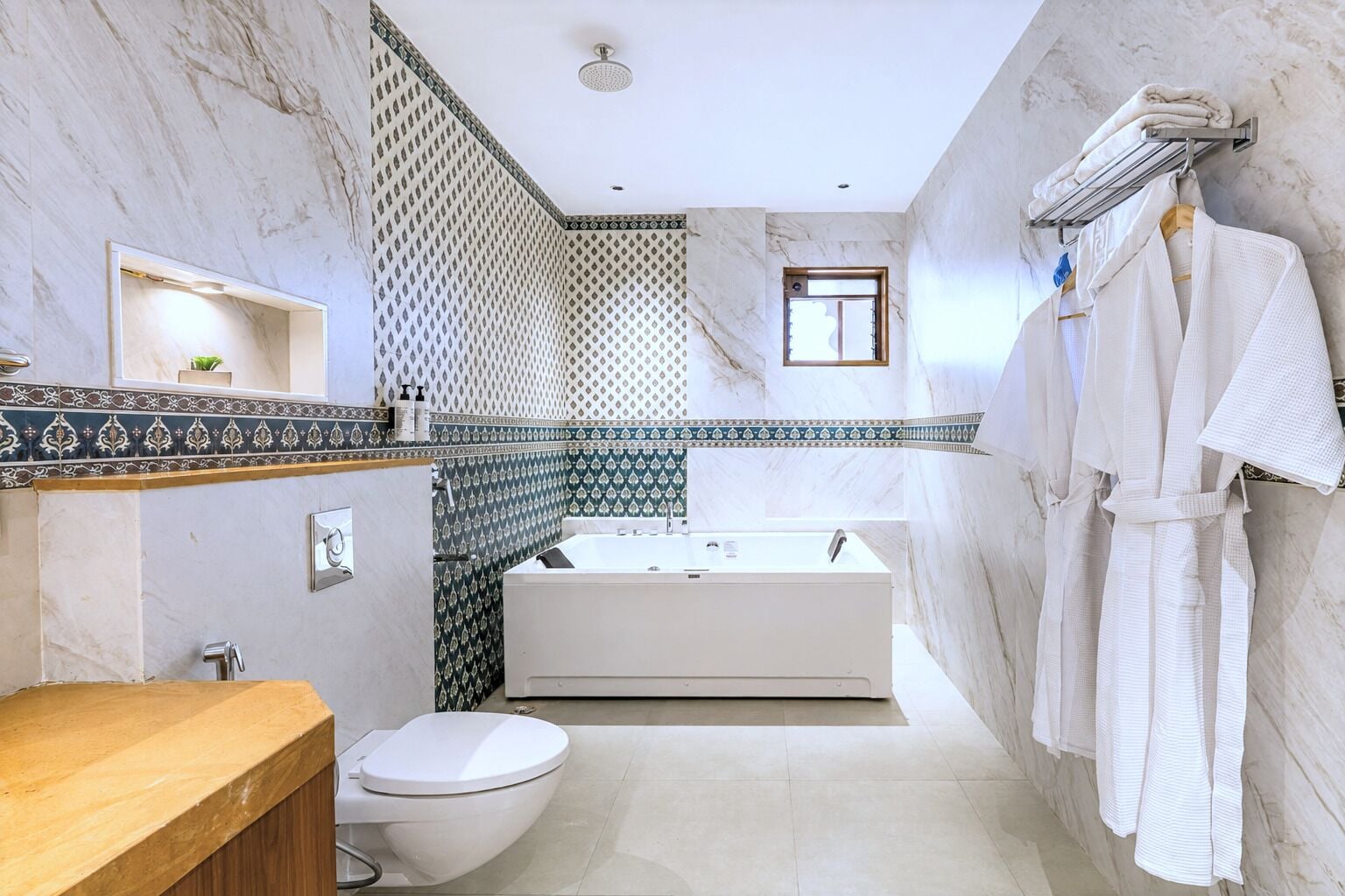 Een badkamer met een bad, toilet en een handdoekrek met handdoeken.