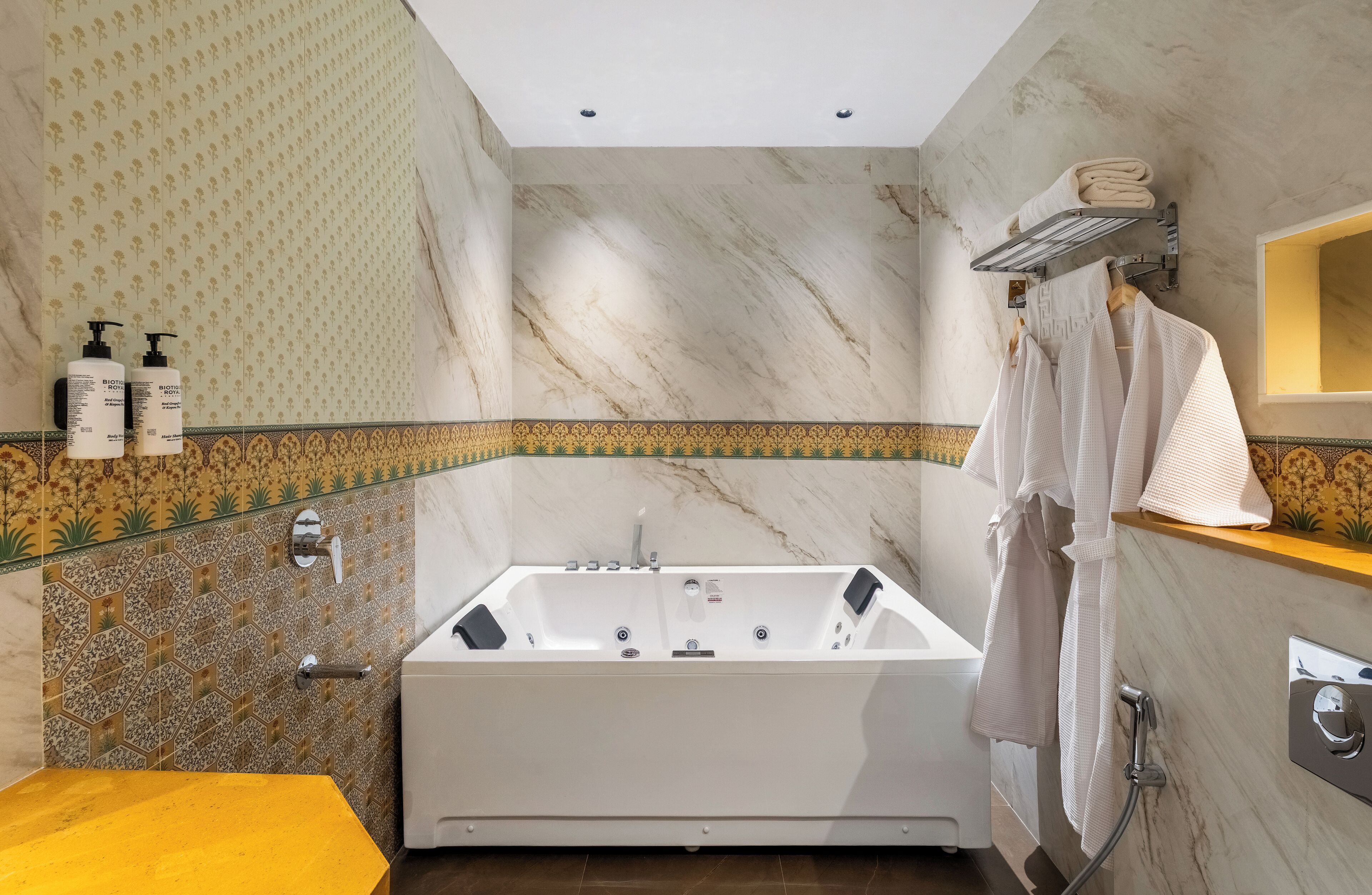 A modern bathroom with a marble wall, a large bathtub, a yellow sink, and a towel rack.