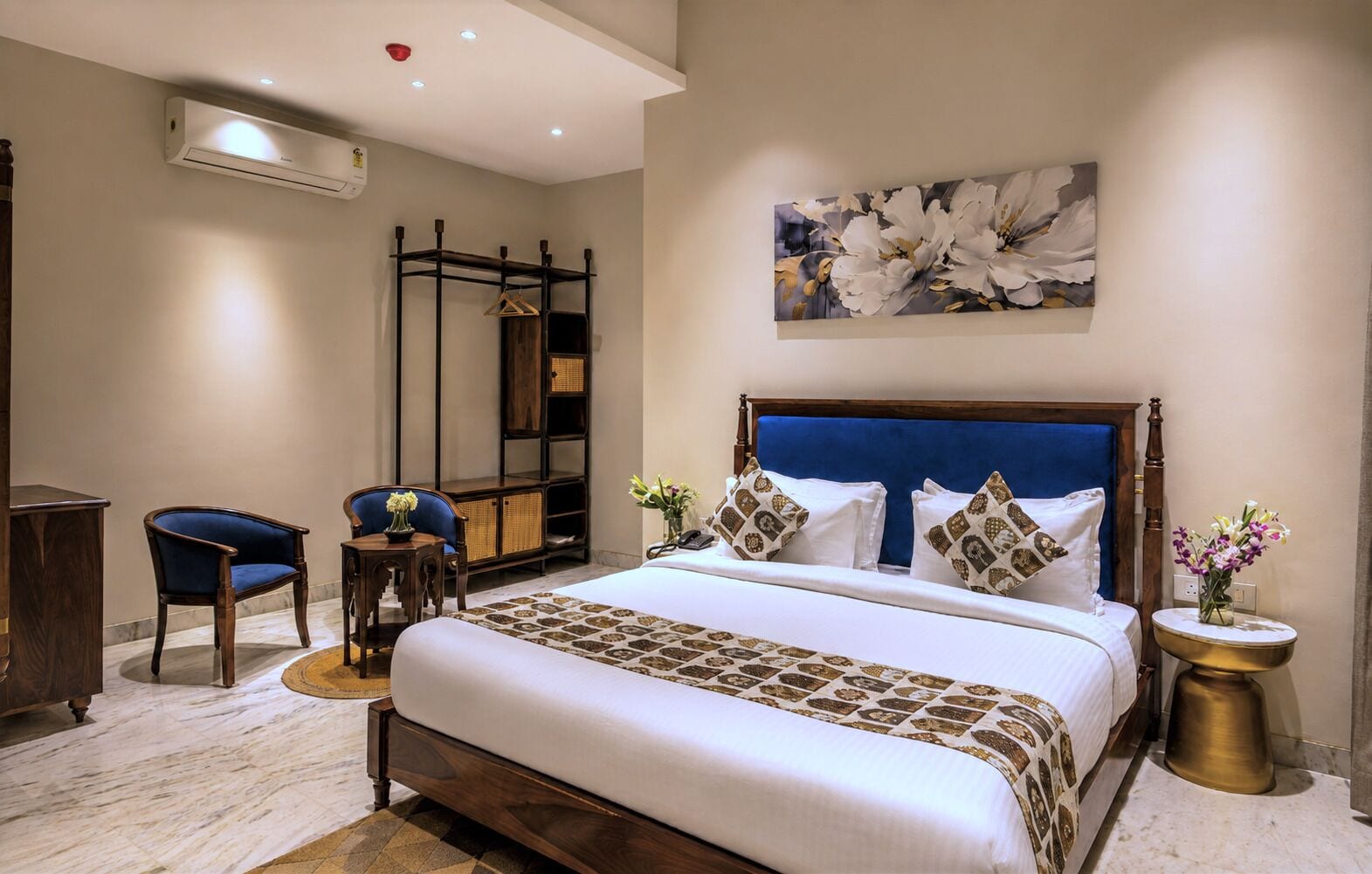 Habitación de hotel con una cama grande, un escritorio, una silla y un aire acondicionado instalado en la pared.