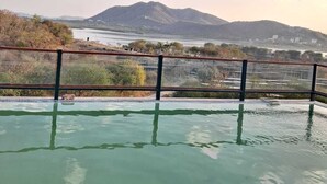 En infinitypool med utsikt över ett bergskedja och en sjö eller ett hav.