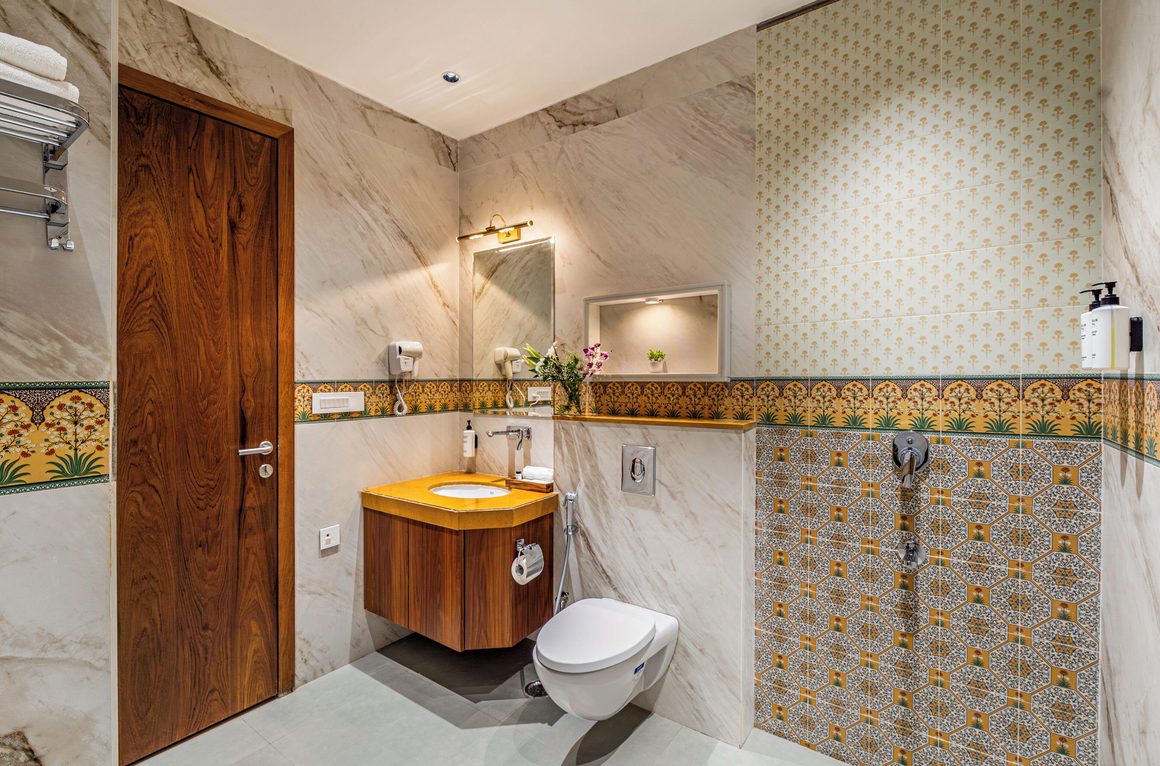 A bathroom with a wooden door, a sink with a mirror, a toilet, and a shower area.