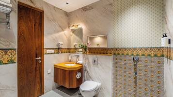 A bathroom with a wooden door, a sink with a mirror, a toilet, and a shower area.