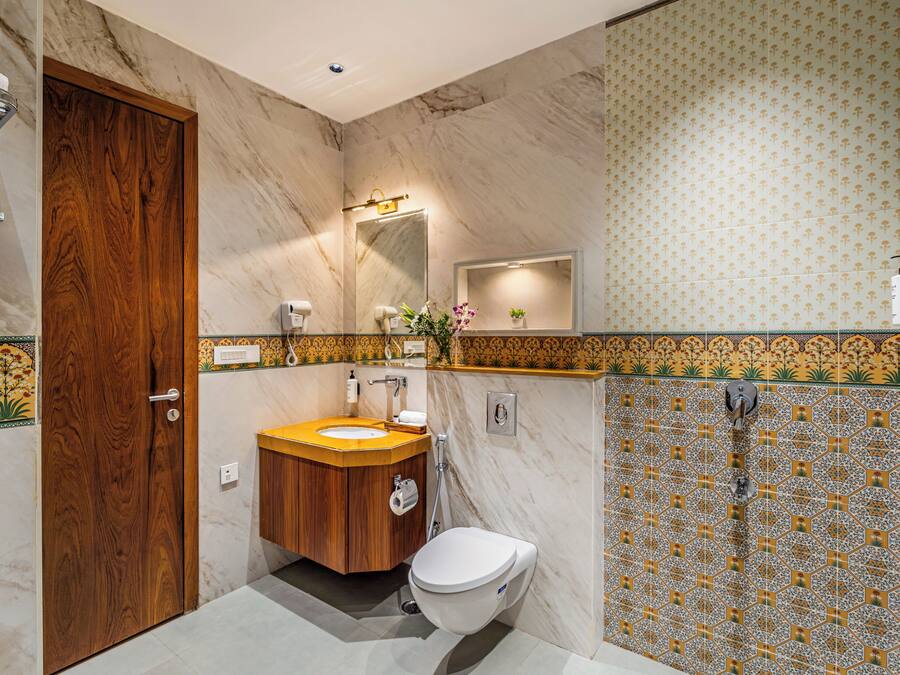 A bathroom with a wooden door, a sink with a mirror, a toilet, and a shower area.
