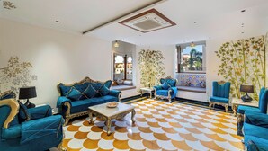 Uma sala de estar ampla com sofás azuis, um piso estampado e vista para o exterior.