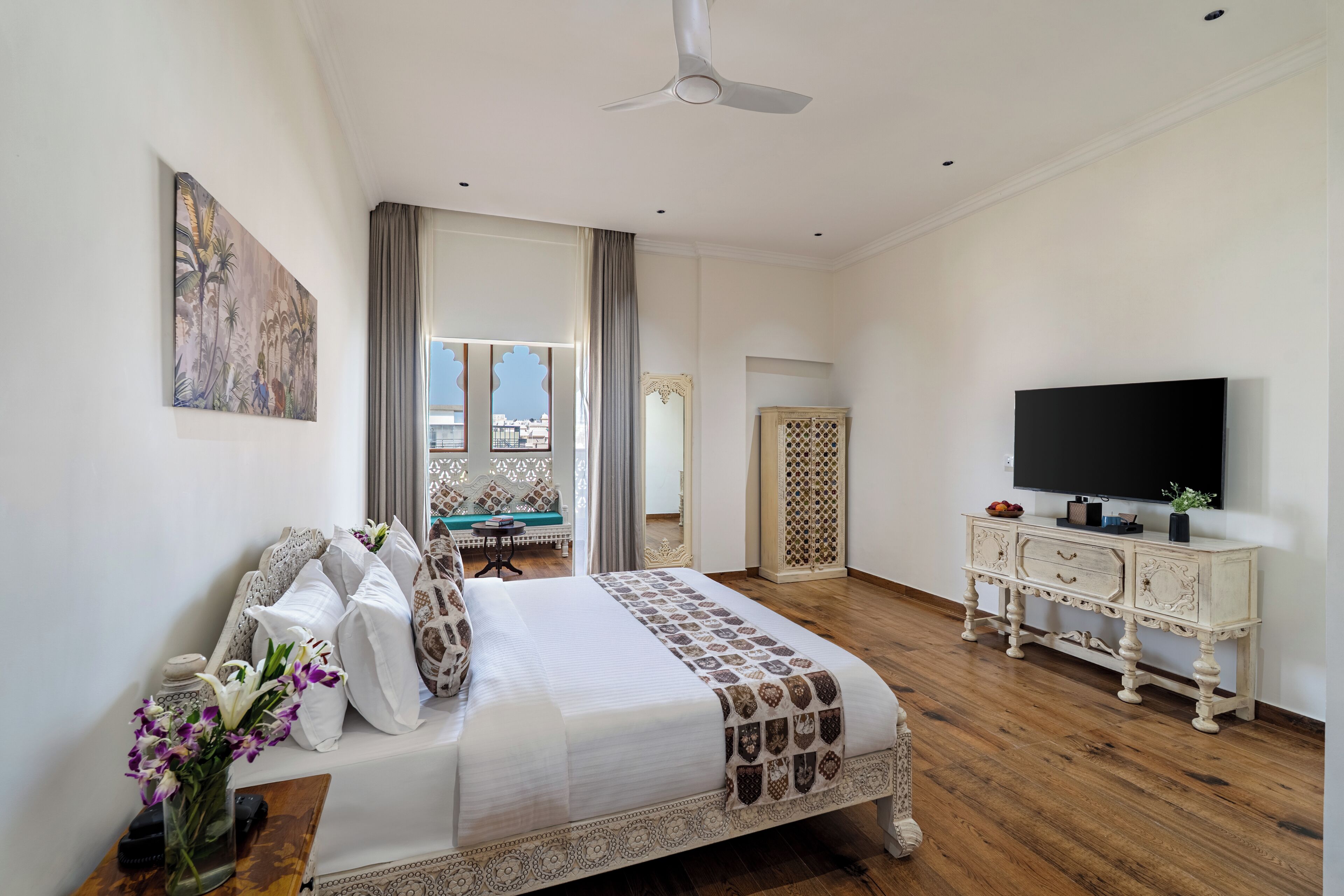Un dormitorio con una cama, televisor, cómoda y un cuadro en la pared.