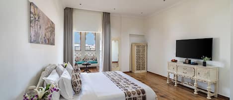 Un dormitorio con una cama, televisor, cómoda y un cuadro en la pared.