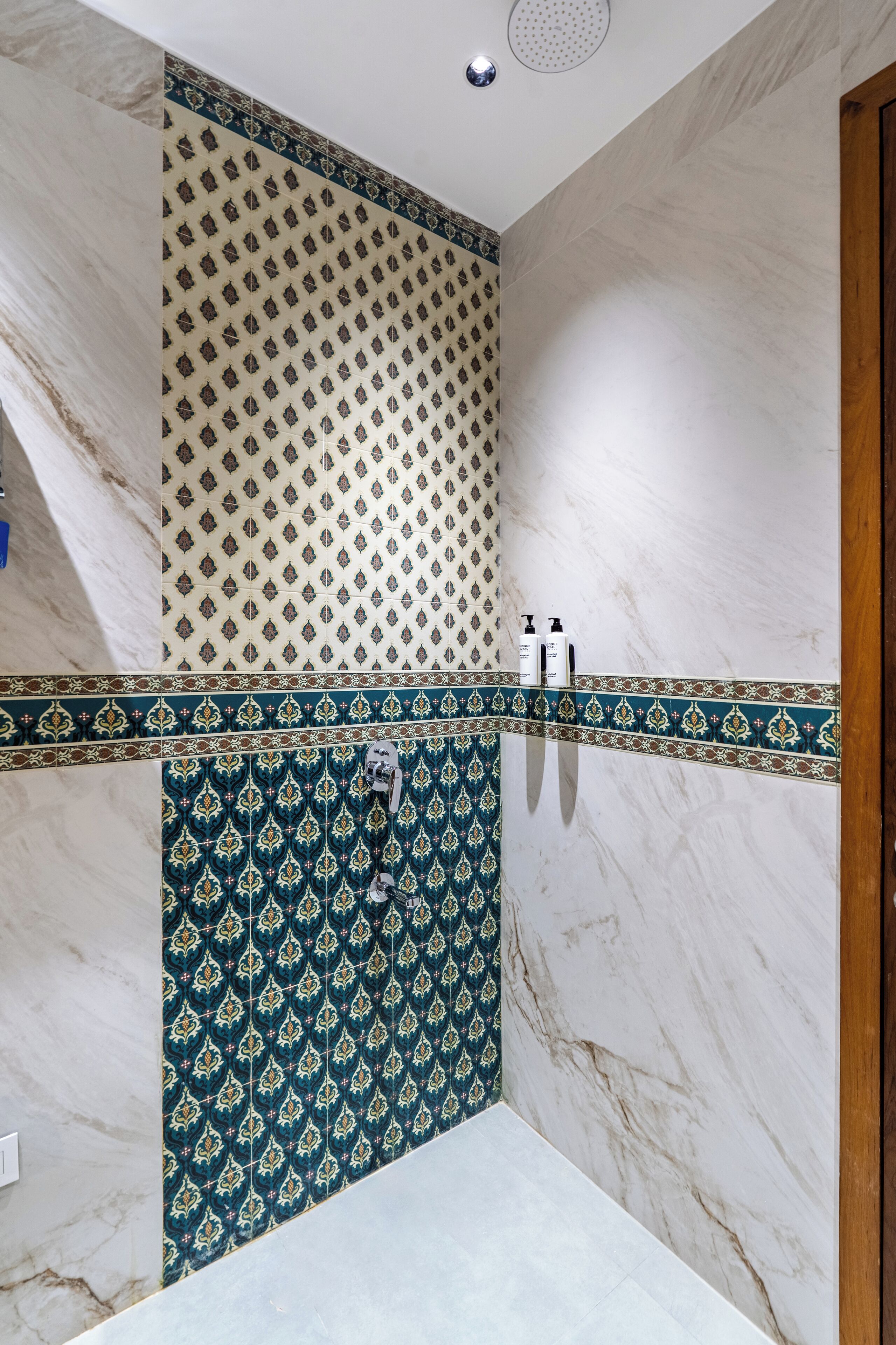 A bathroom with a marble wall, a patterned tile backsplash, and a shower area.