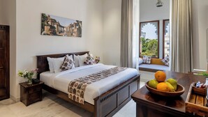Quarto bem arrumado com cama, mesa de cabeceira e janela com cortinas.