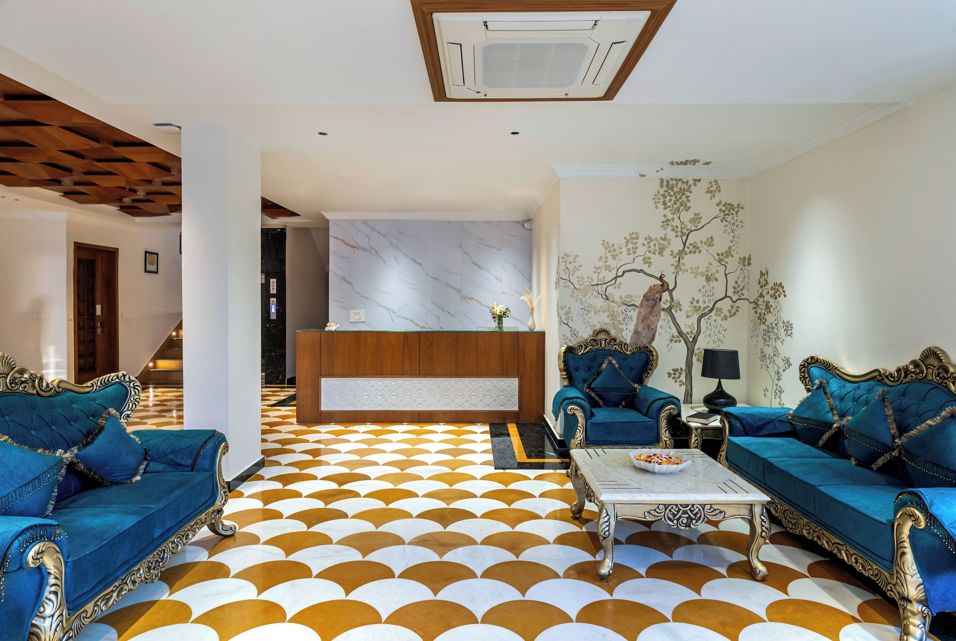 A lobby with a check-in desk, two sofas, a coffee table, and a patterned floor.