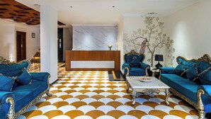 Um hall de entrada com uma mesa de recepção, dois sofás, uma mesinha de centro e um chão estampado.