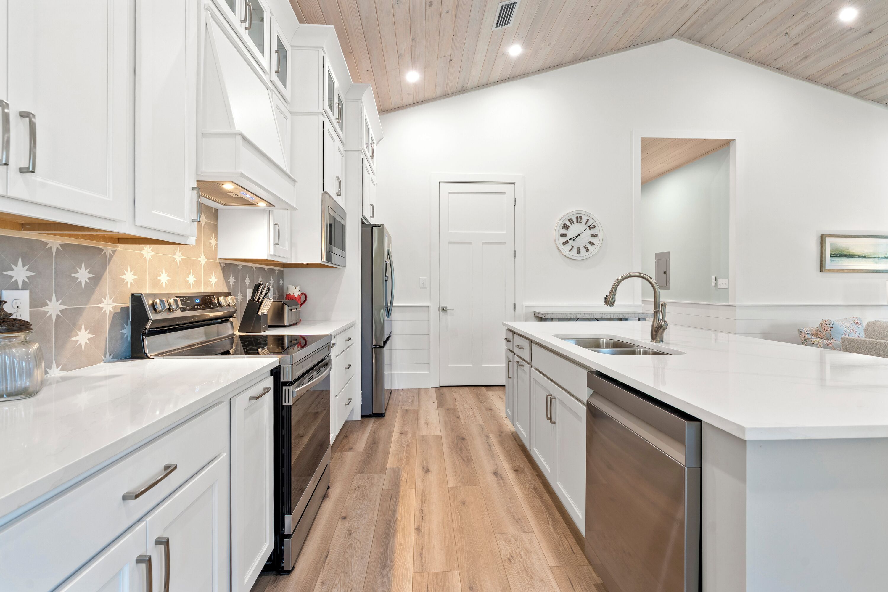 Une cuisine moderne avec des meubles blancs, des appareils en acier inoxydable et un plancher en bois.