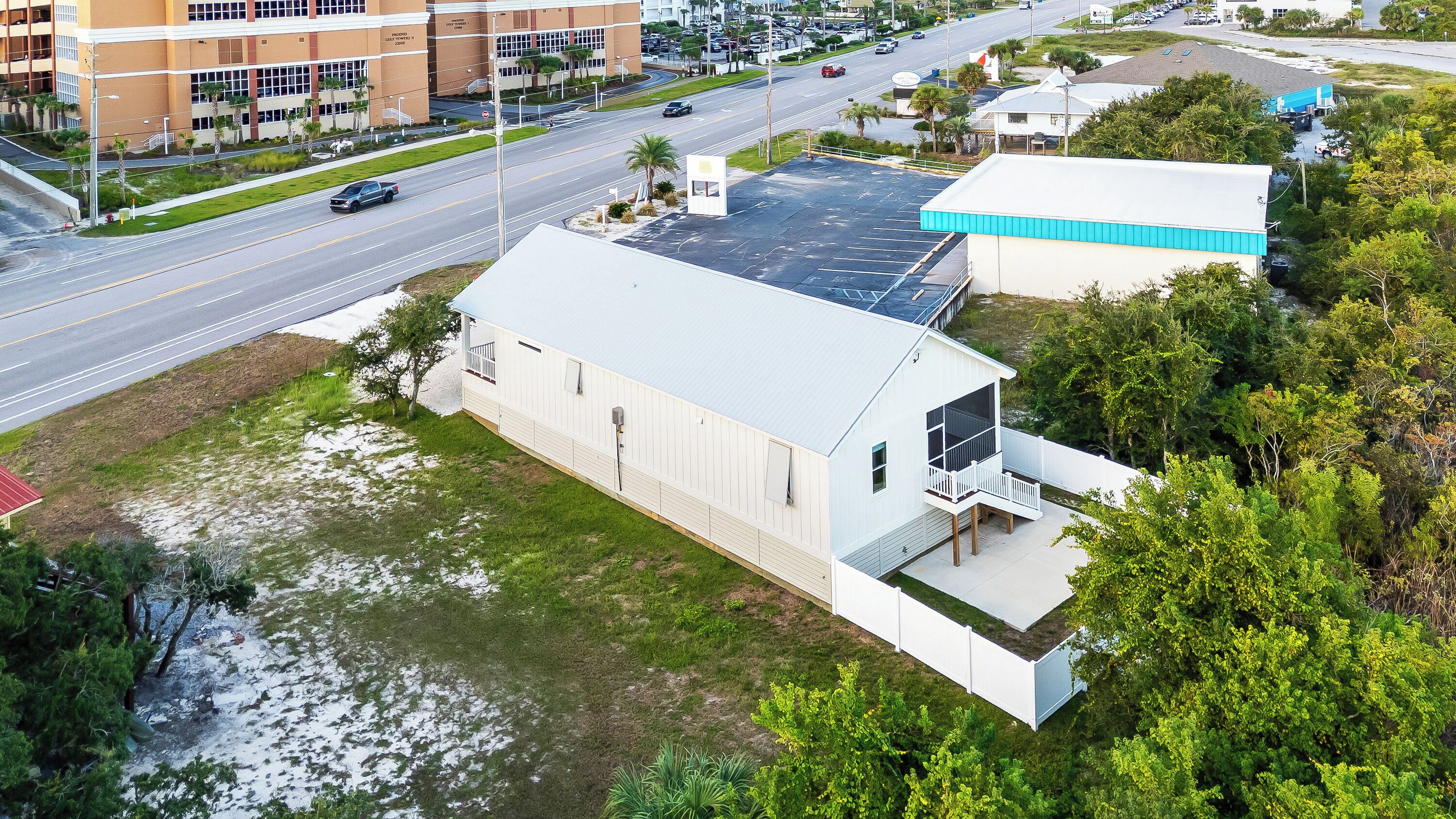 An aerial view of a building with a flat roof, adjacent to a road with vehicles.