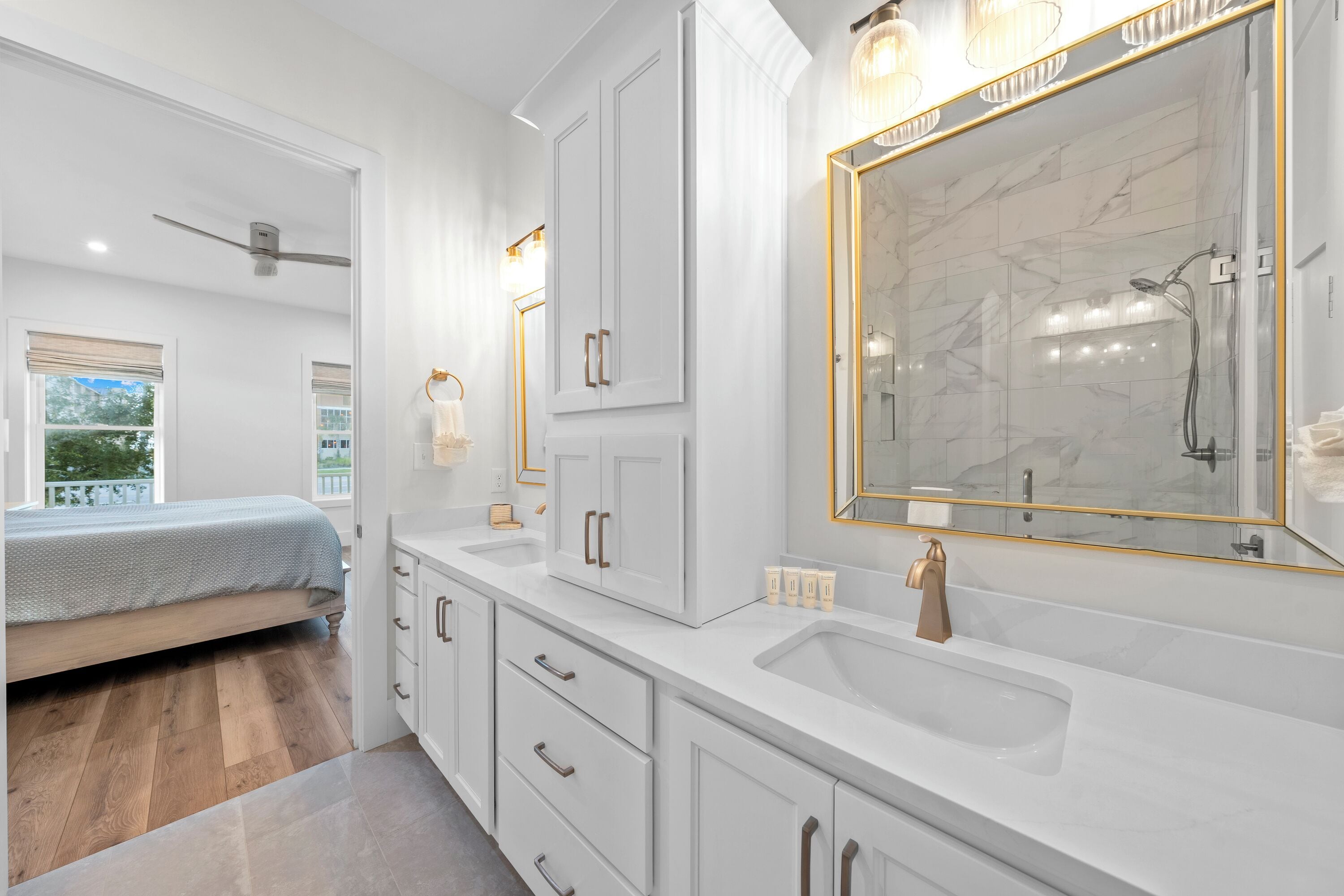 A modern bathroom with a large mirror, white cabinetry, and a shower area.