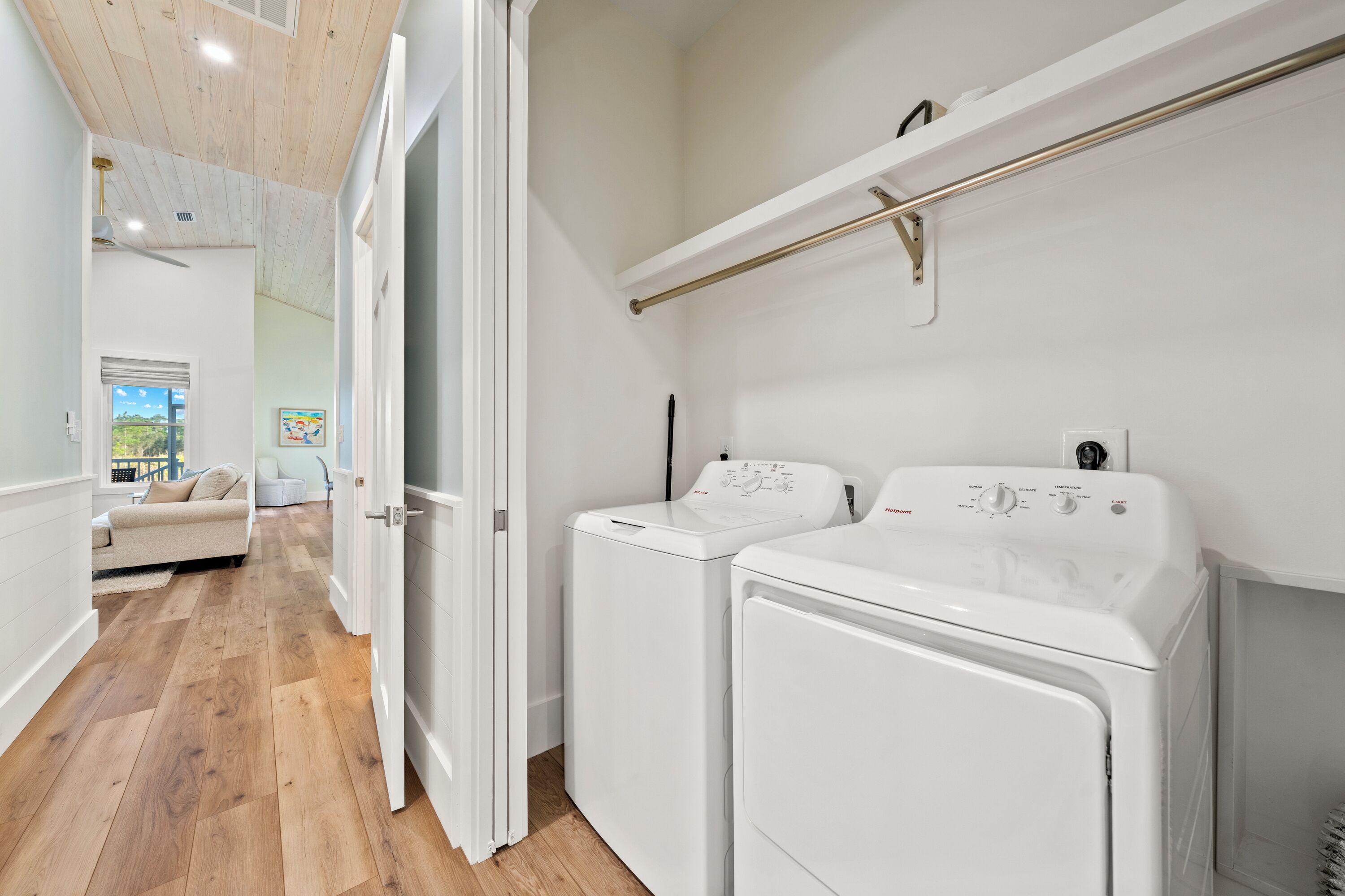 A laundry room with two white washing machines, a wooden floor, and a white ceiling.