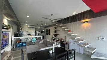 Penthouse superior, balcón, vista a la ciudad | Área de sala de estar | Televisión de pantalla plana y monitor de computadora