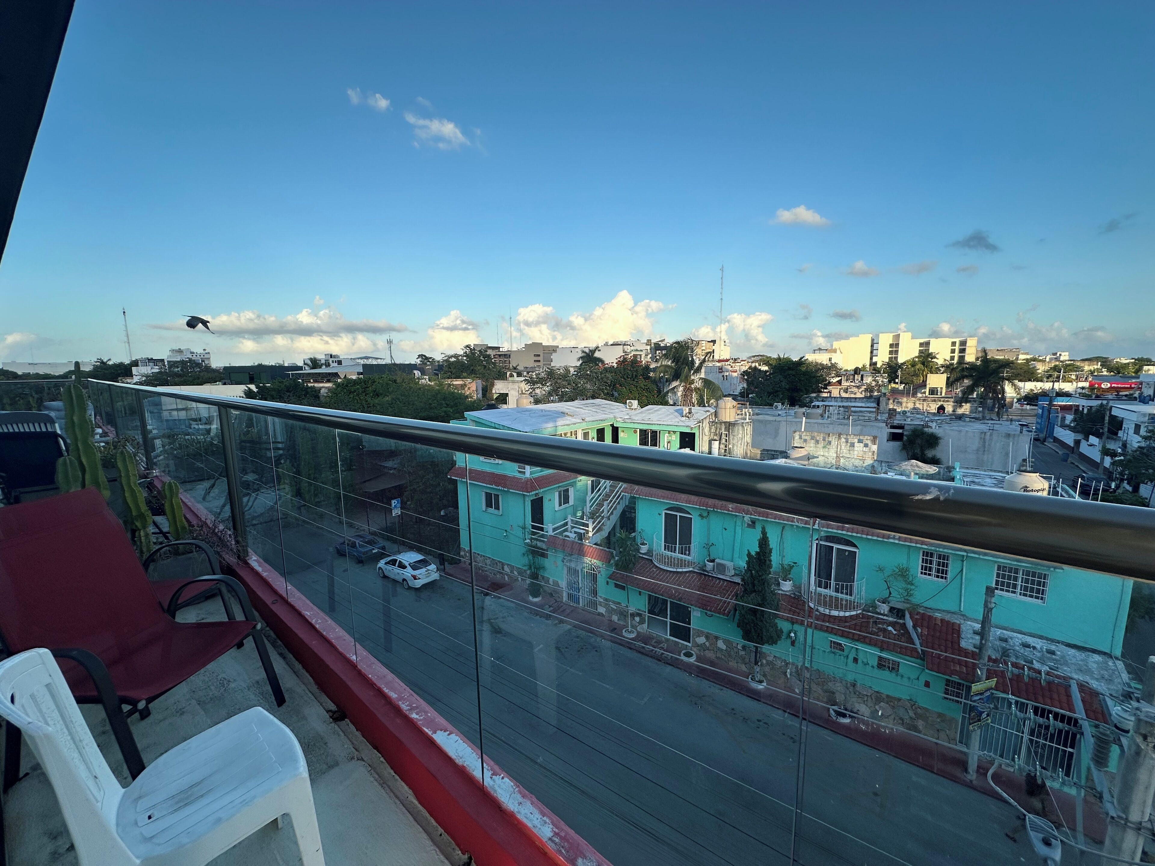 A balcony with a clear view of a cityscape, including buildings and a road with cars.