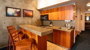 A compact kitchen with wooden cabinets, a granite countertop, a microwave, and a sink. There are two framed pictures on the wall. - Ski-in-ski-out Snowbird, X-large studio, Alta, LCC Hot Tub, Heated Pool (Snowbird)