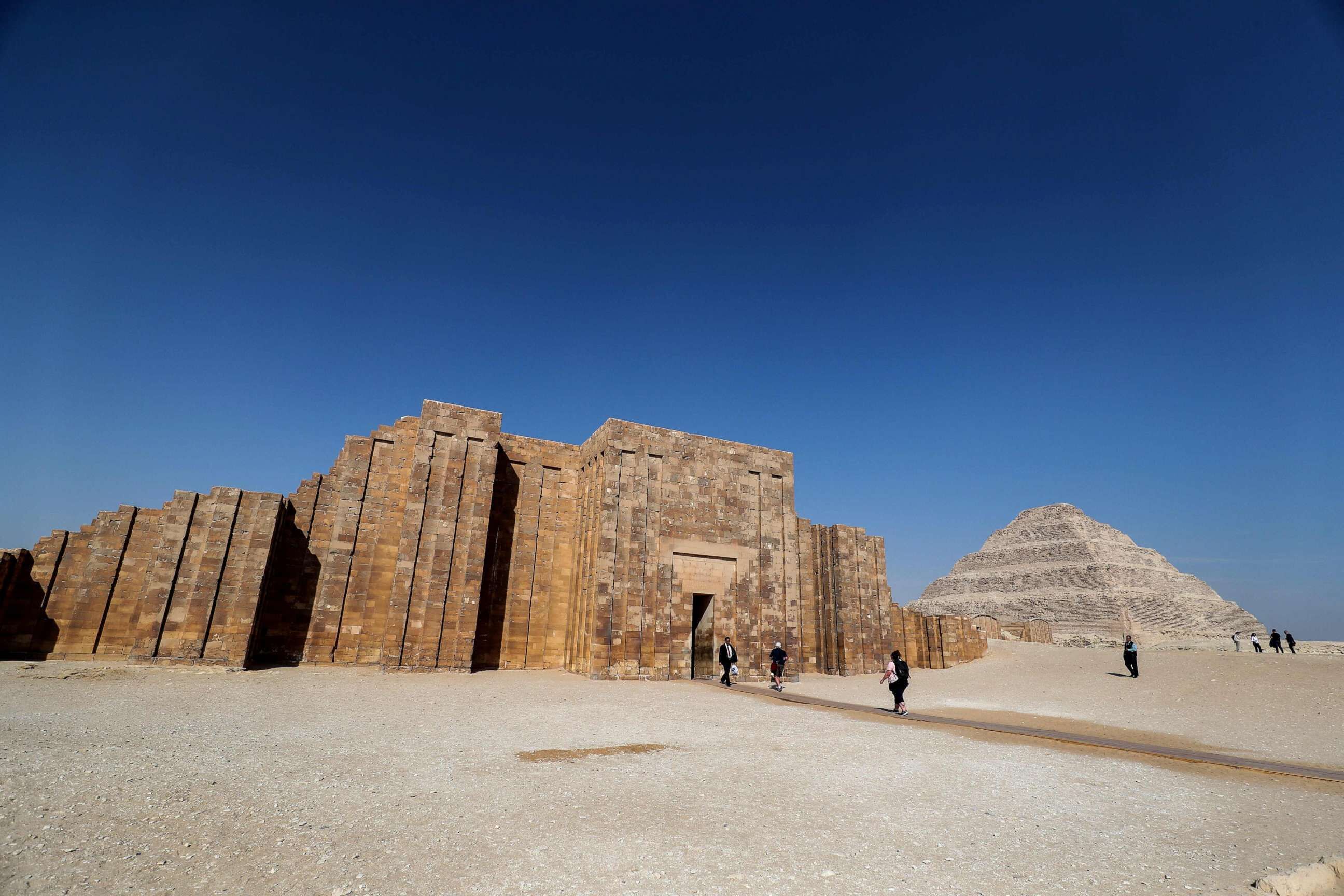 A large ancient stone structure with a pyramid in the background.