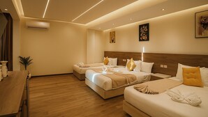 A hotel room with two beds, a wooden dresser, a small table, and a wall-mounted air conditioner. - Nefri Pyramids Hotel (Giza)