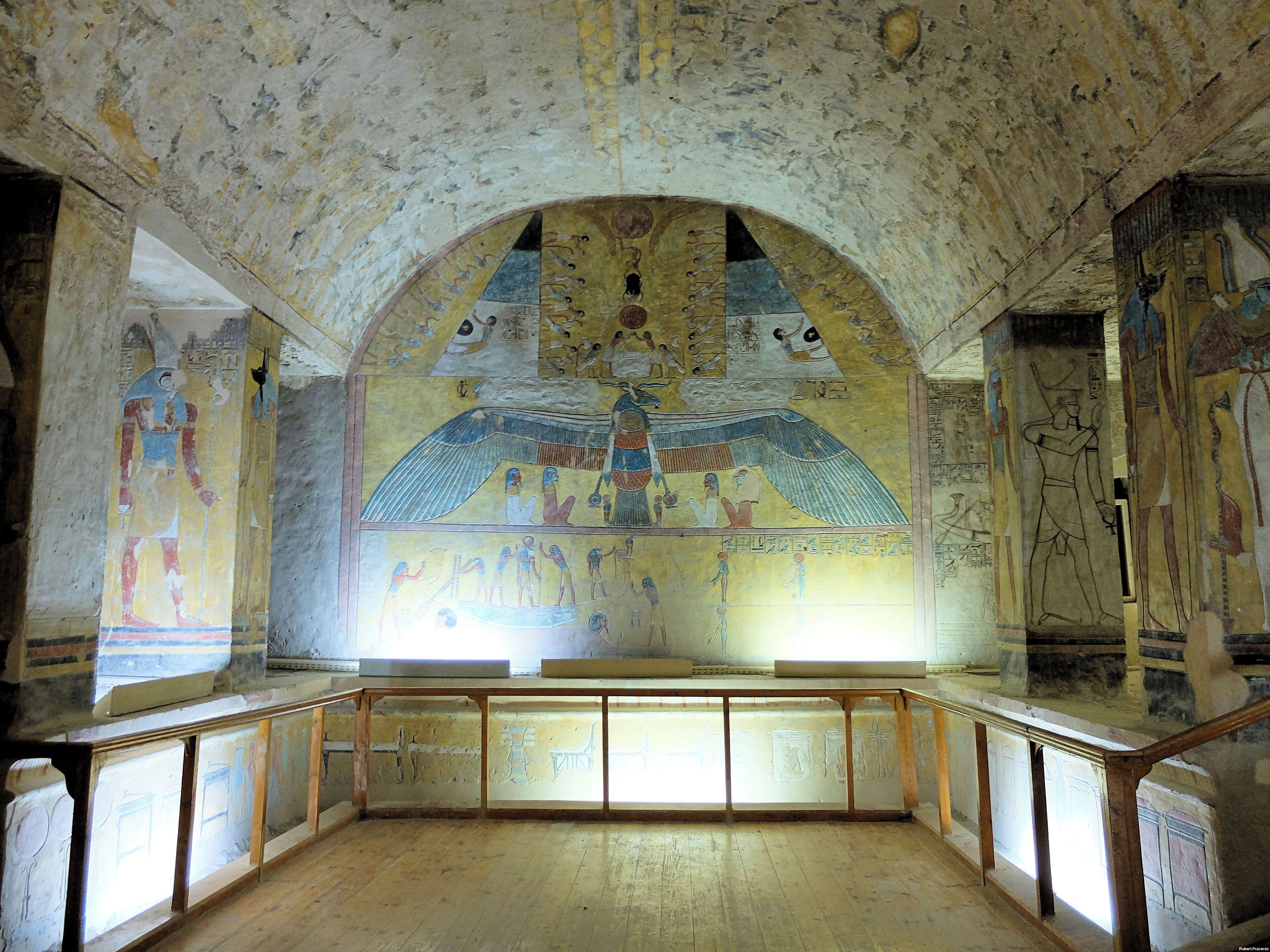 An interior with a central mural, wooden benches, and a staircase.