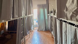 A corridor with bunk beds, a tiled floor, and a window with curtains. - Sundiva Guest House (Patong)