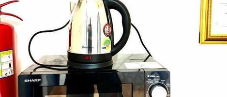 A kitchen with a toaster oven, a kettle, and a fire extinguisher.