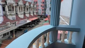 A balcony with a view of colorful buildings and a clear sky. - Sundiva Guest House (Patong)