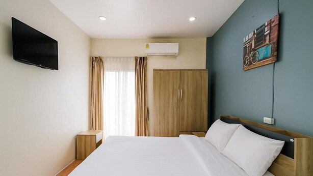 A hotel room with a bed, a TV, an air conditioner, and a painting on the wall. - Sundiva Guest House (Patong)